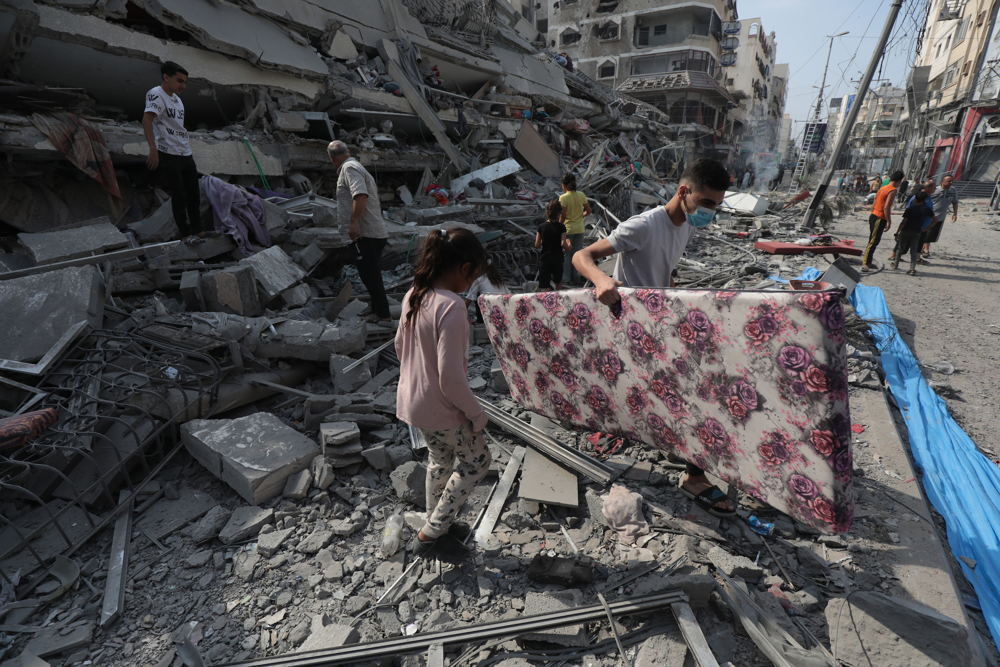 A Reuters photo shows a young boy and girl clutching a salvaged mattress amid shattered concrete​